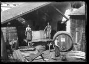 Ripresa in esterno. Tre uomini davanti a botti di legno in un bottaio. Su una botte l'iscrizione 