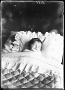 Ritratto, un bambino morto in un letto con piumino