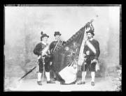 Ripresa in studio. Ritratto di gruppo di tre uomini in uniforme con una bandiera con l'iscrizione 