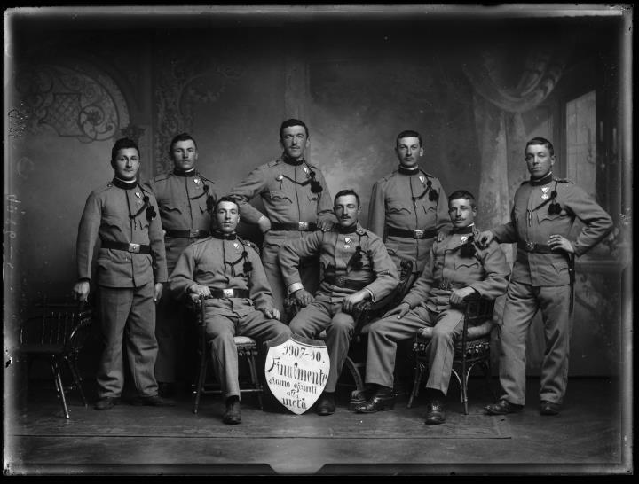 Ripresa in studio. Ritratto di gruppo di soldati in uniforme con uno scudo con la scritta 