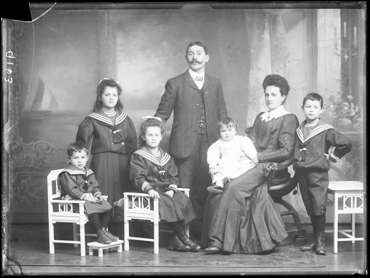 Studioaufnahme. Gruppenporträt: stehend: ein Mann und ein Mädchen, sitzend: eine Frau und vier Kinder. Die Kinder tragen Matrosenanzug