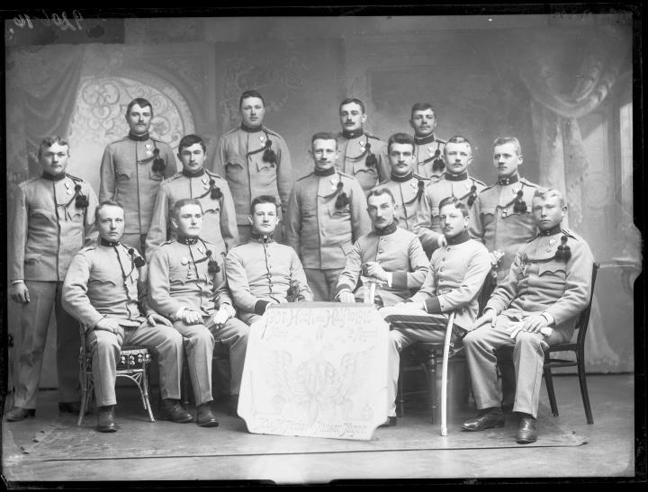Studioaufnahme. Gruppenporträt von Soldaten in Uniform mit einer Tafel mit der Aufschrift 