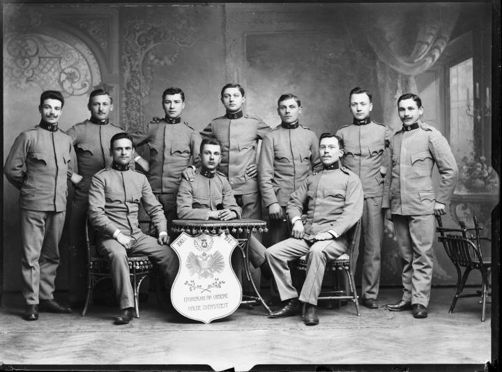 Studioaufnahme. Gruppenporträt von Soldaten in Uniform mit einer Tafel mit der Beschriftung 