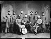 Ripresa in studio. Ritratto di gruppo di soldati in uniforme con una lavagna dove compare la scritta 