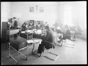 Ripresa interno. Donne e uomini sedute davanti a scrivanie con la macchina da scrivere