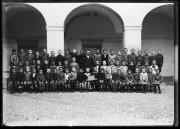 Ripresa in esterno. Ritratto di gruppo di un gruppo di studenti della Knabenschule, 8a classe, con un maestro al centro. Un ragazzino tiene una lavagna con la scritta 