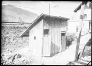 Außenaufnahme. Holzverschlag. Im Hintergrund ein Mann und ein Gebäude