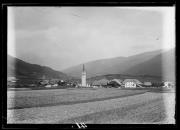 Ripresa in esterno: Ampio campo con paese,  chiesa, case