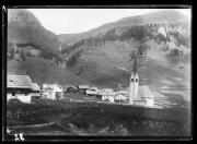 Ripresa in esterno. Paesaggio di montagna con paese, una chiesa, un ampio campo e dei soldati in uniforme che camminano in fila.