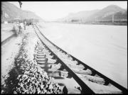 Außenaufnahme. Hochwasser am Fluss Etsch, vom Wasser unterspülte Gleise, mehrere Männer