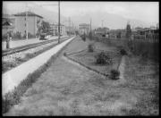 Ripresa in esterno. Paese, strada, un uomo, carri ferroviari. Un'insegnia con l'iscirzione: 