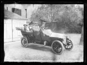 Ripresa in esterno. La famiglia Waldmüller in automobile: Josefine Unterweger, sposata Waldmüller, (17.06.1870-27.10.1938) siede sul sedile posteriore, al suo finco la figlia Imma con il cane, il marito Dr. Robert Waldmüller, amministratore dell'ospedale di Bolzano, (1864-1936), fratello del fotografo Hermann Waldmüller, il figlio Robert al volante. Dietro di esso un edificio con la scritta 