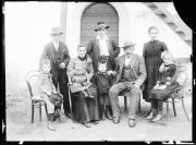 Ripresa in esterno. Ritratto di gruppo: tre uomini, due donne, quattro bambini. Dietro di loro una porta con il numero 4