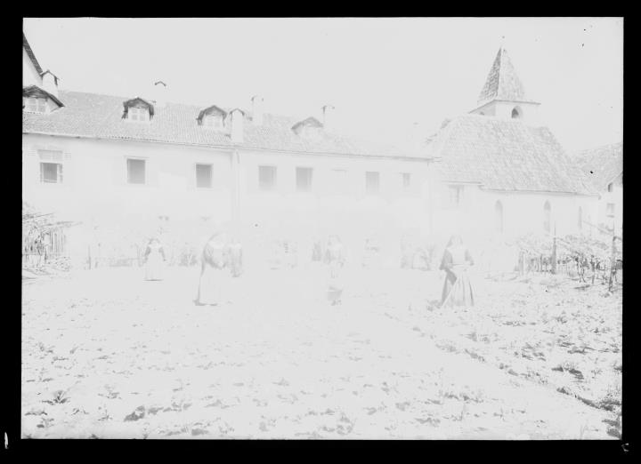 Außenaufnahme. Mehrere Nonnen arbeiten in einem Garten neben der St. Anna Kirche in St. Michael/Eppan